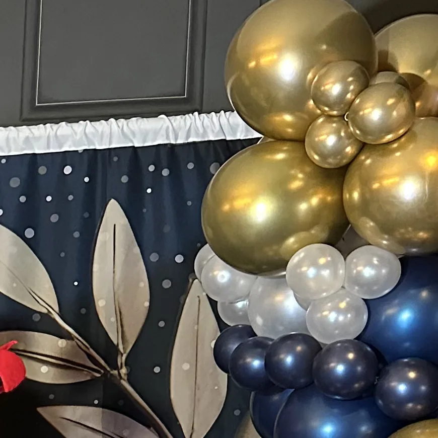 A gold and navy balloon garland beside the booth backdrop at one of our events.