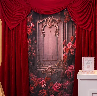 Red rose backdrop framed by deep red velvet curtains.
