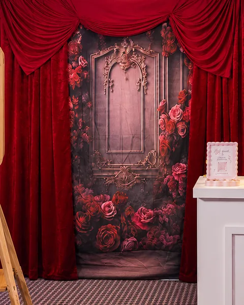 A rose backdrop framed by red velvet curtains.