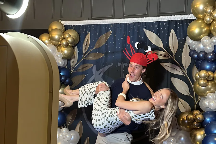 Guests posing together beside the booth at an event.