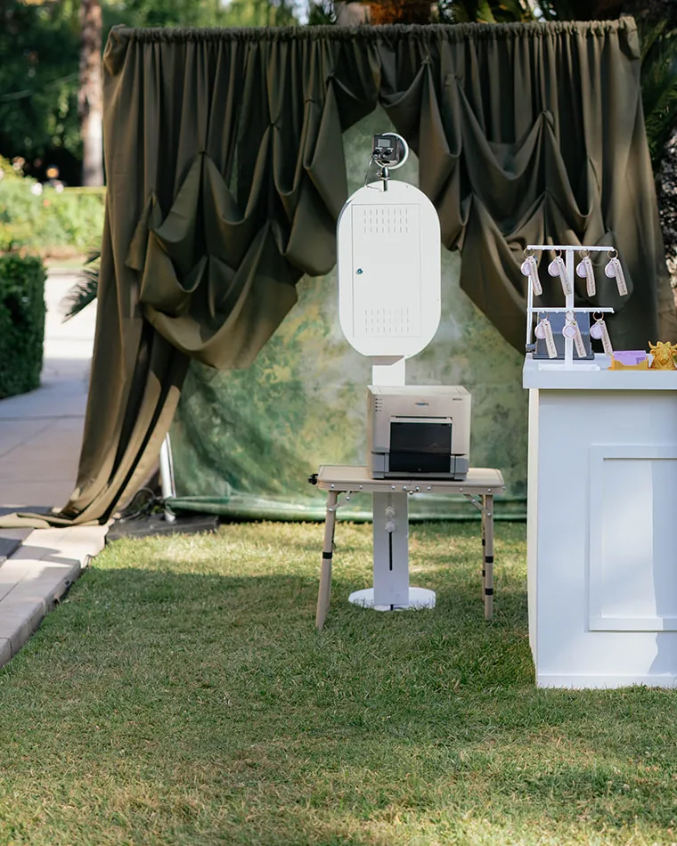 The open air booth and printer in front of a draped outdoor backdrop.
