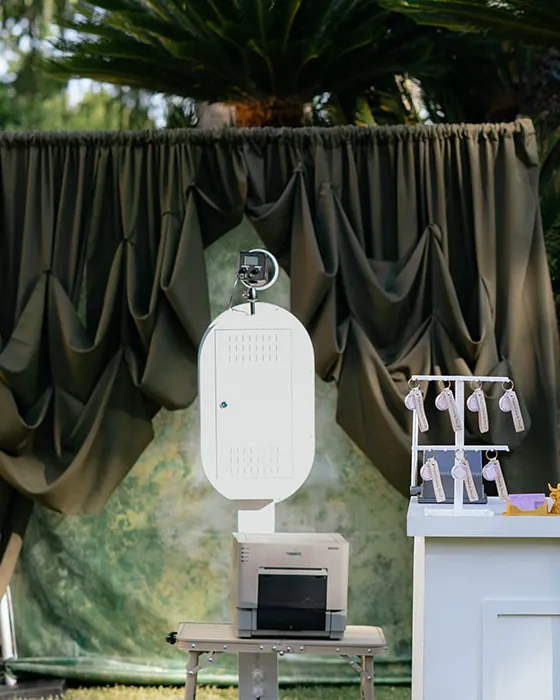 The open air booth and its printer set up on a lawn beside the olive drape.