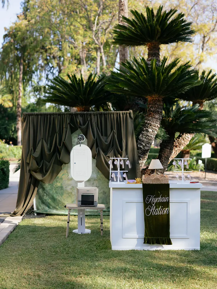 The open air booth and the Keychain Station set up on a lawn under the palms.