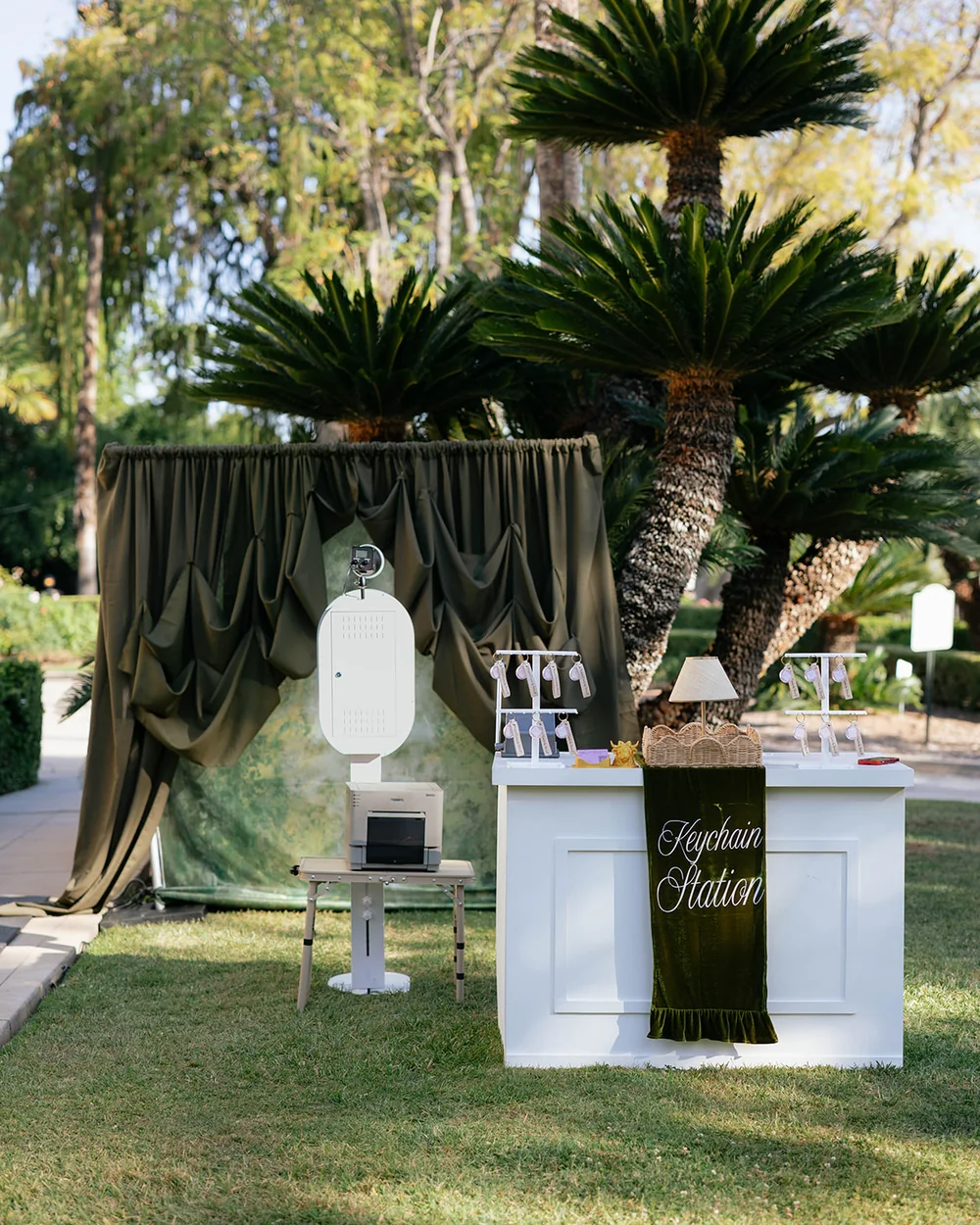 The open air photo booth, printer and keychain bar set up on a lawn before guests arrive.