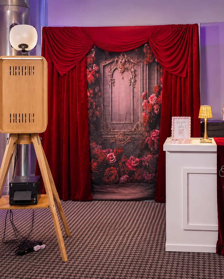 The open air photo booth and its photo printer in front of a rose floral backdrop.