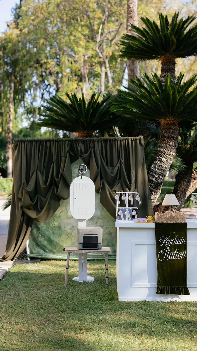 The open air photo booth set up beside a draped backdrop at an outdoor garden event.