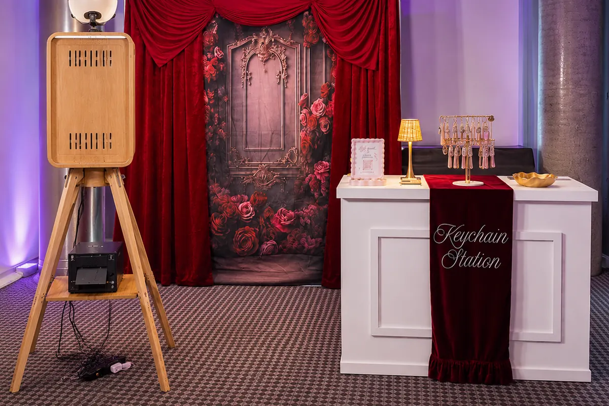 The booth on its tripod and the Keychain Station bar in front of a red velvet backdrop.