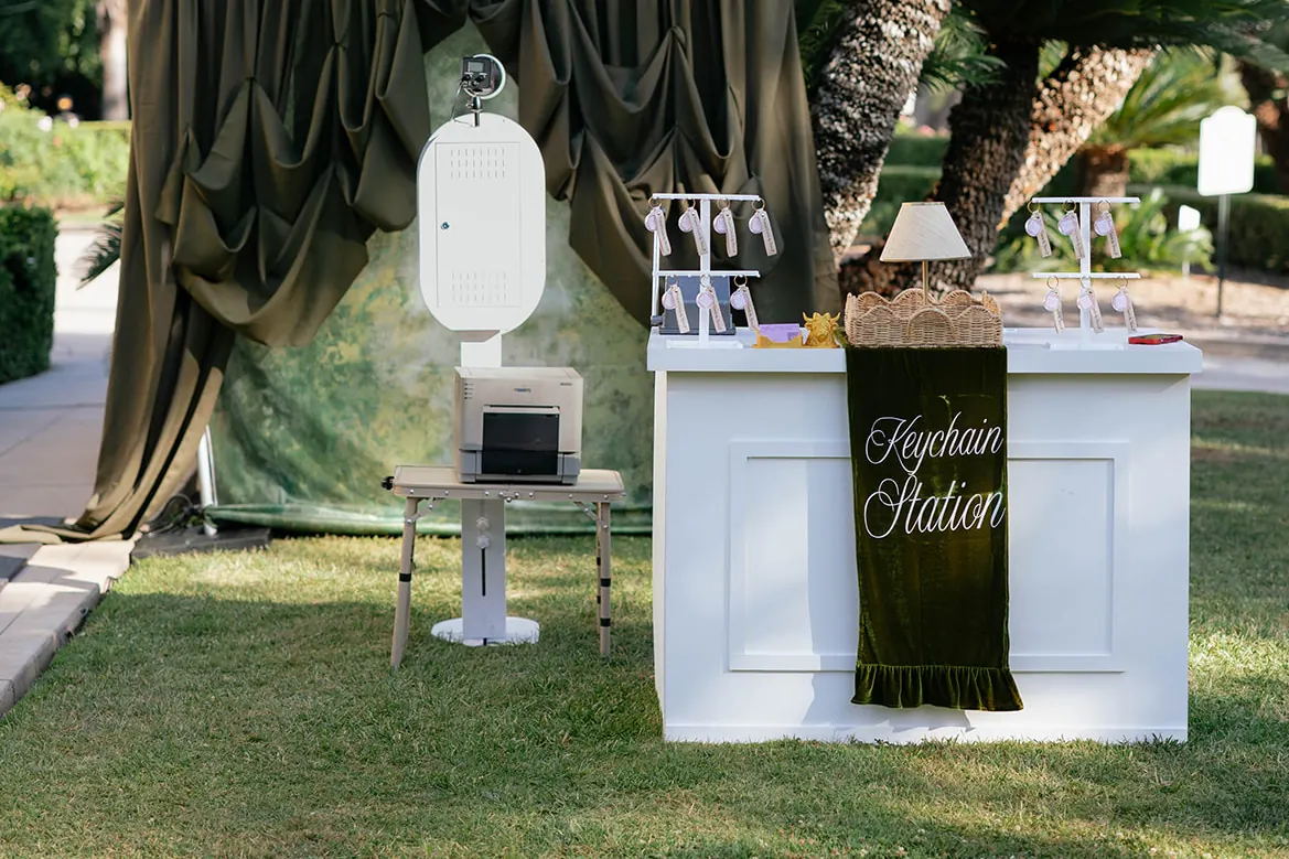 The booth, its printer and the Keychain Station set up on a lawn beside a hedge.
